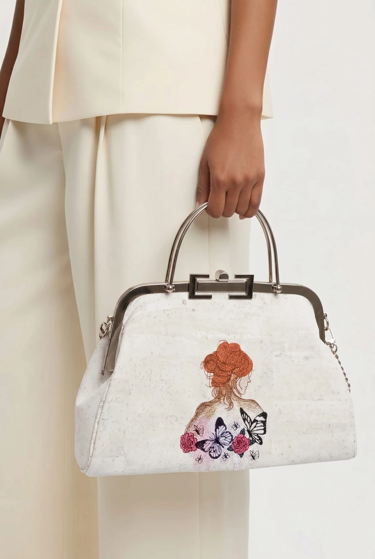 Sac L'Affichette porté à la main avec une tenue ivoire